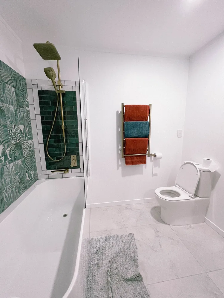 Gleaming bathroom with white tub, tiles and fresh towels