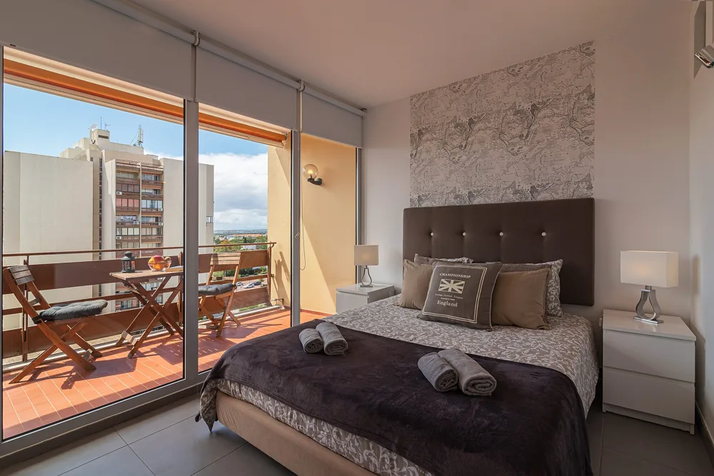 Bright bedroom with freshly made bed and sunny balcony